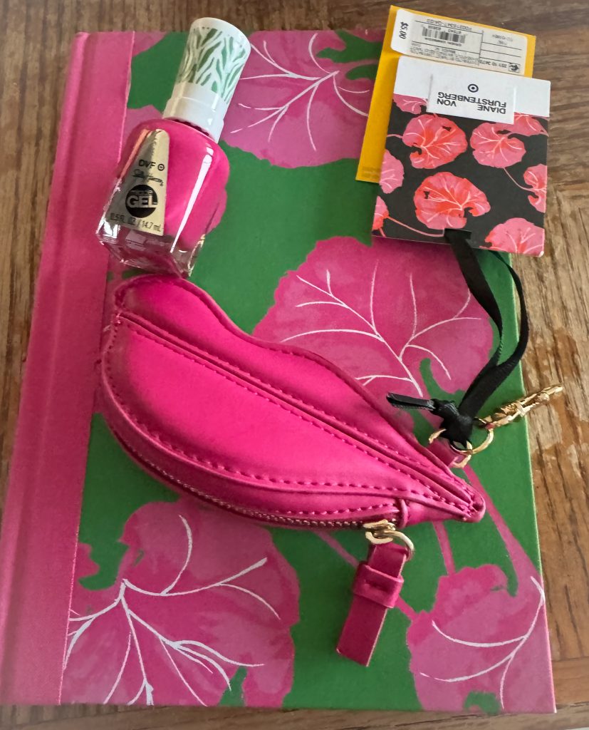 Nail polish and a coin purse on a notebook with pink flowers on it.