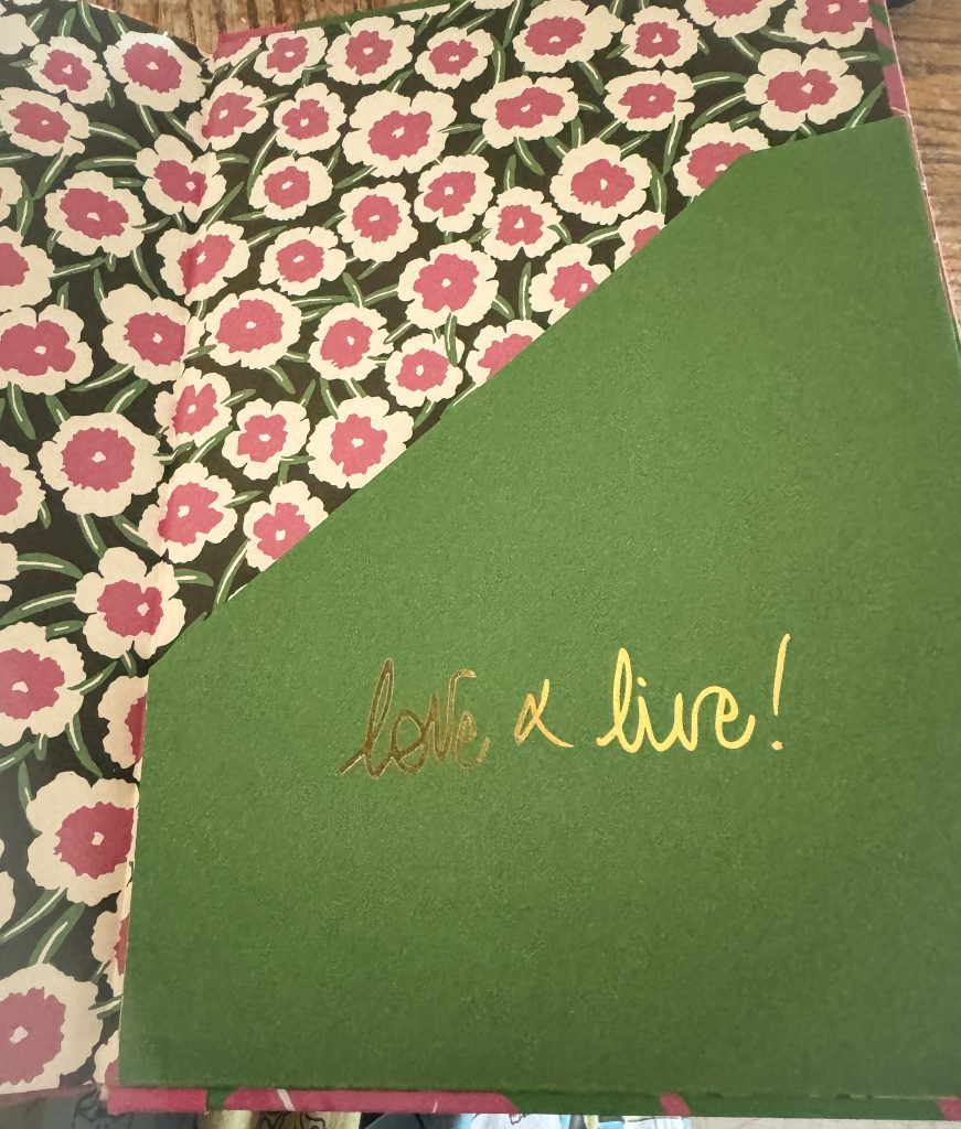 Inside flap of the notebook with pink and white flowers and the words”love and live”